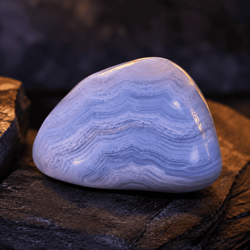 Polished blue agate stone with layered patterns on dark background.